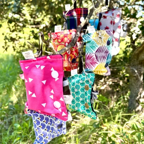 Pochettes suspendues pour sacs à crottes de chien. Colorées et portant une étiquette Leenia, entreprise française.