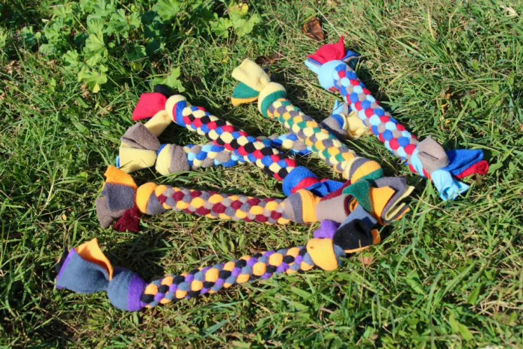 Plusieurs jouets pour chiens en tas. Jouets tressés de type scoubidou. Couleurs orange, violet, noir, gris, rouge, vert...