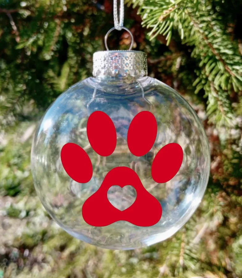 Boule de Noël en plexiglas faite à la main en France. Motif rouge de coeur dans une patte de chien.